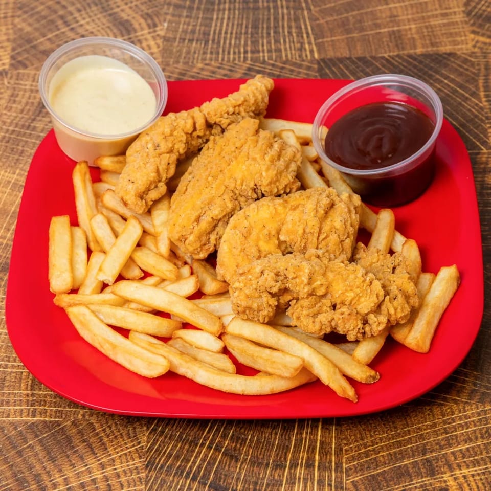 Crispy chicken tenders and golden french fries on a red plate with two dipping sauces.